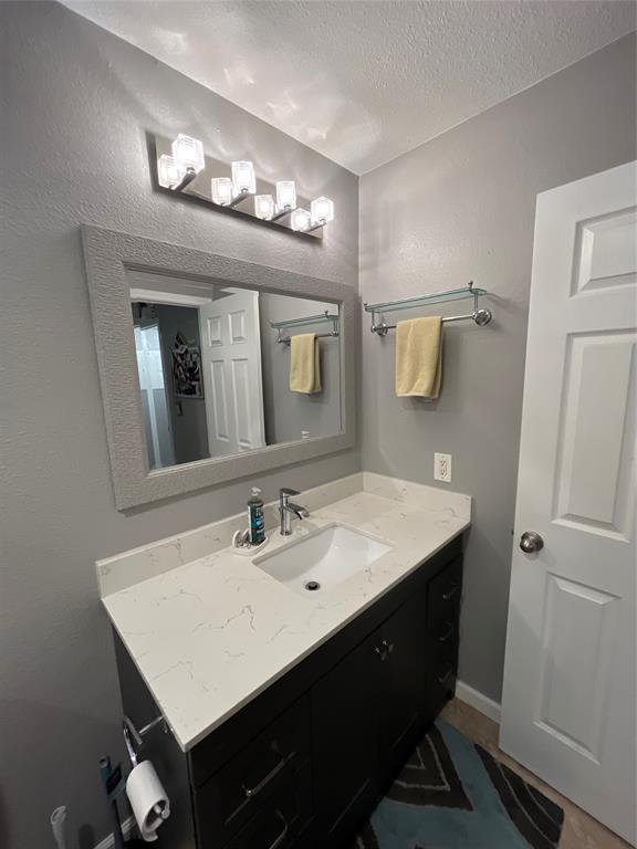 1705 Crossing Place, Unit 131 Austin, TX 78741 - Photo 11 of 13 a bathroom with a sink a light fixture and a mirror