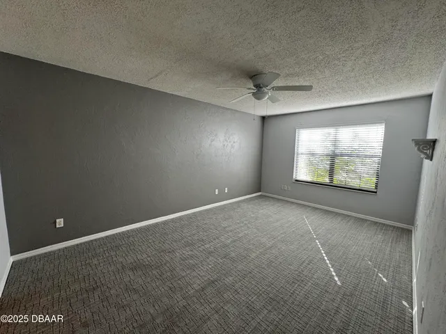 an empty room with windows and ceiling fan