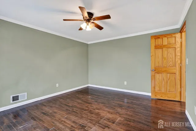 an empty room with wooden floor fan and windows
