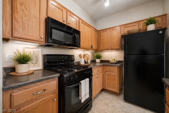 6320 Snap Ridge Street, Unit 201 North Las Vegas, NV 89081 - Photo 4 of 56 A compact kitchen with light wooden cabinetry offers modern black appliances and ample counter space.