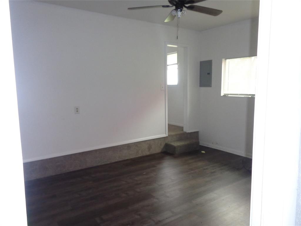 612 South Files Street Itasca, TX 76055 - Photo 7 of 30 Empty room featuring dark wood-style flooring, electric panel, and a ceiling fan