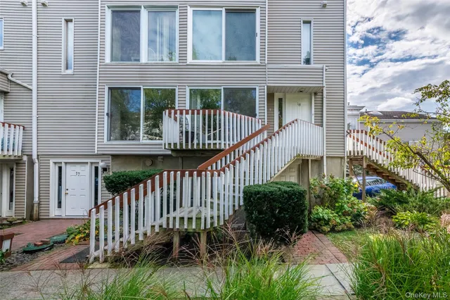 a view of a house with wooden fence next to a yard
