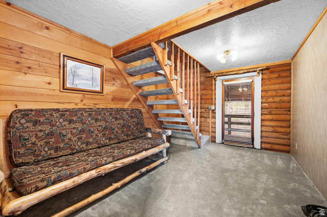 4725 Pine Ridge Road Evanston, UT 82930 - Photo 43 of 82 Interior space featuring a carpeted staircase with wood railings, log walls, wood-paneled walls, and carpet flooring