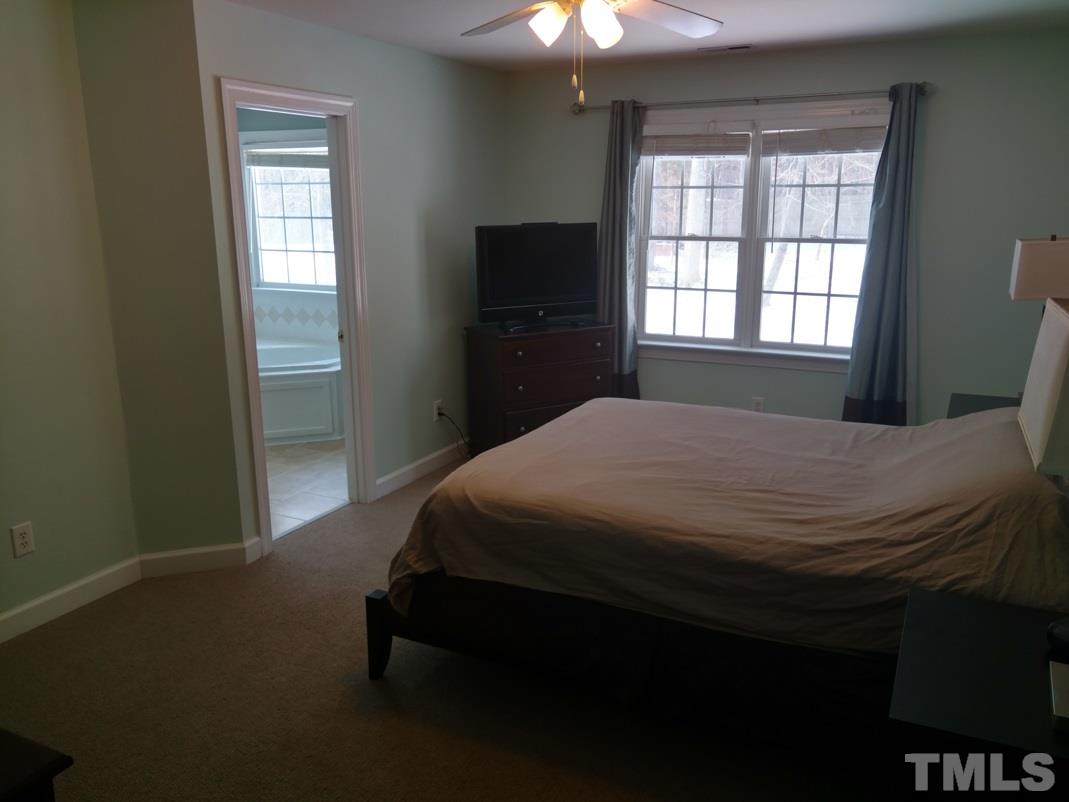 9425 Stone Mountain Road Raleigh, NC 27613 - Photo 19 of 25 a bedroom with a bed and a flat tv screen on dresser