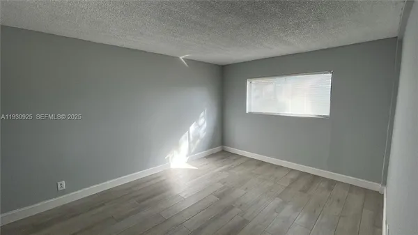 a view of an empty room with wooden floor and closet