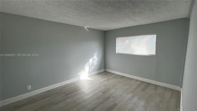a view of an empty room with wooden floor and closet