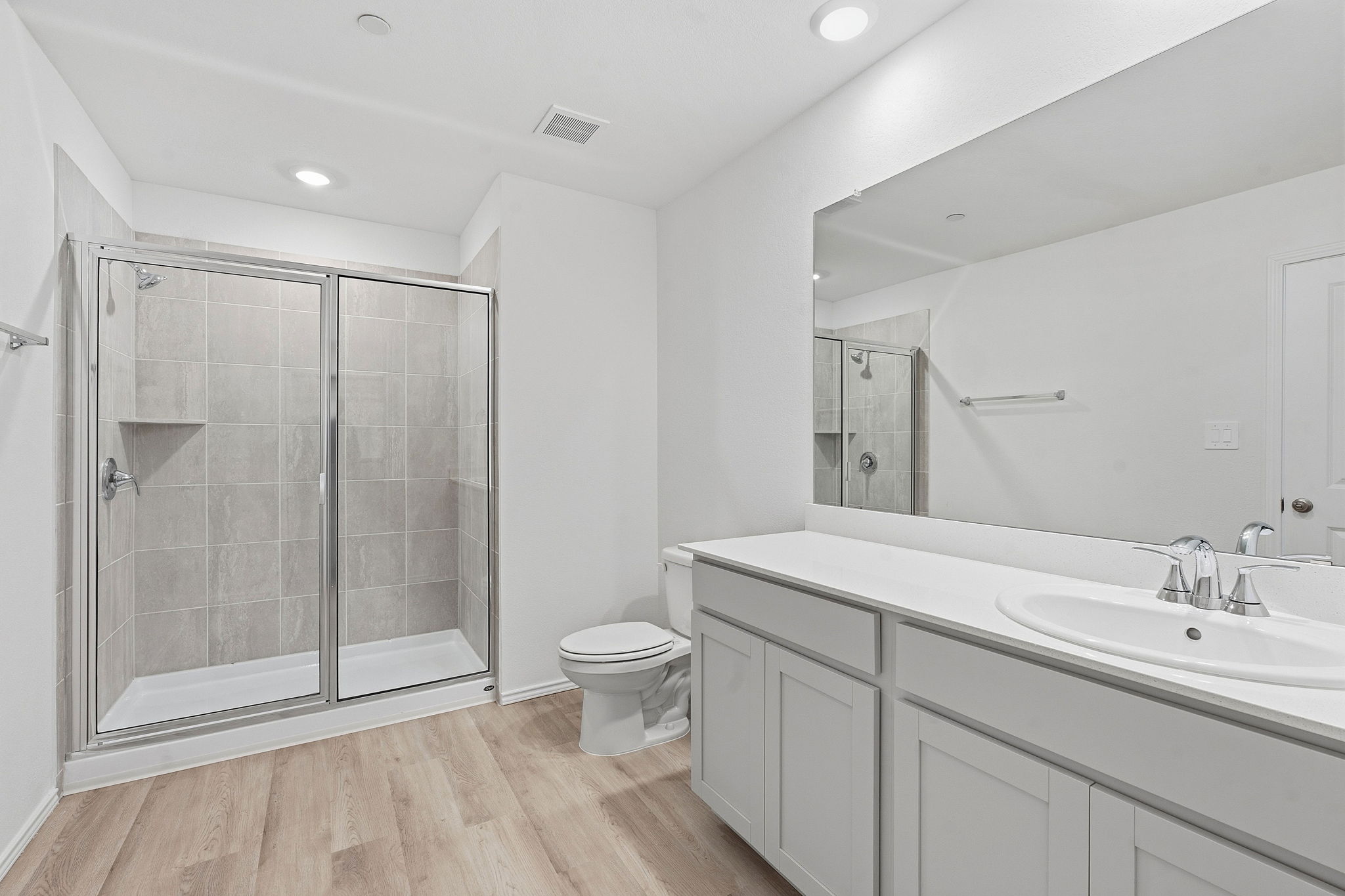 164 Cinnabar Lane, Unit 5 Kyle, TX 78640 - Photo 13 of 21 Bathroom featuring a glass-enclosed shower with tile surround, a single vanity with an undermount sink, and wood-finish flooring
