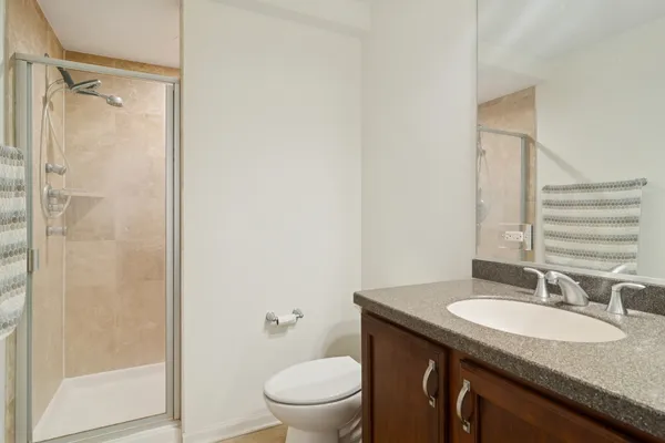 a bathroom with a granite countertop sink toilet and shower