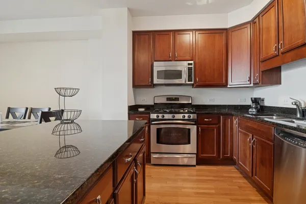 a kitchen with stainless steel appliances granite countertop a stove a sink and a microwave
