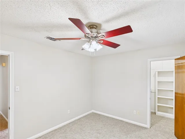 an empty room with a window and a ceiling fan