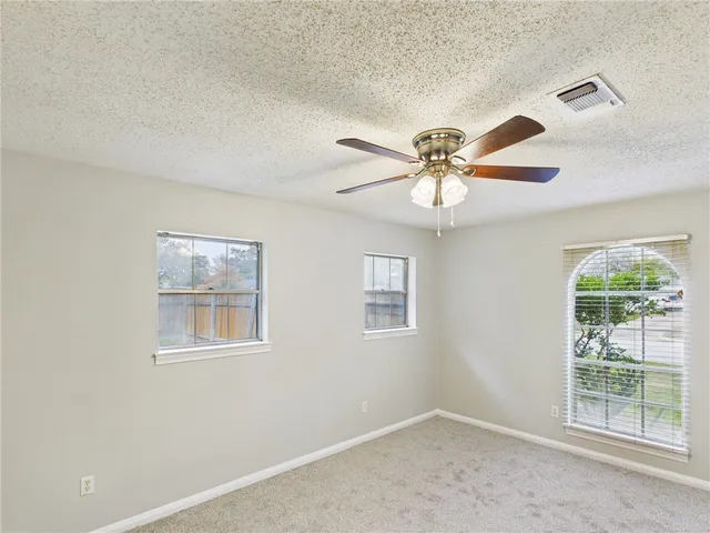 an empty room with windows and fan