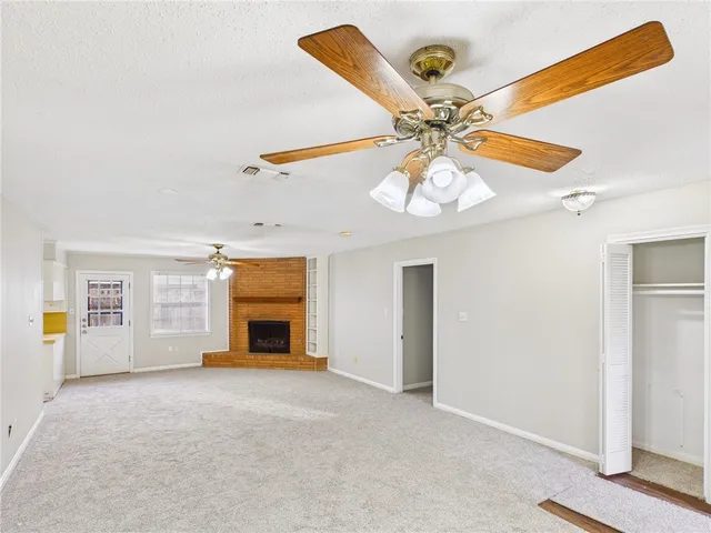 a view of an empty room with window and a kitchen