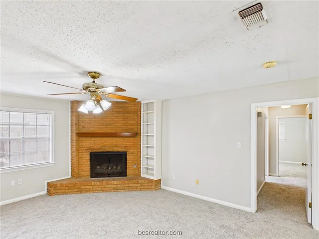 an empty room with windows and fireplace