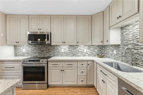 a kitchen with granite countertop white cabinets and stainless steel appliances