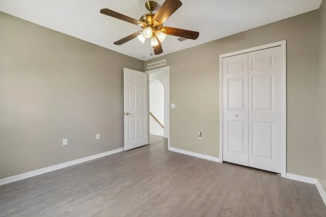 an empty room with closet and a ceiling fan