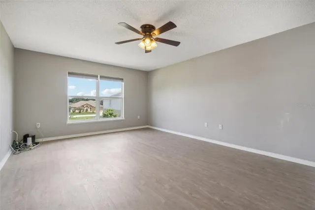 an empty room with windows and ceiling fan