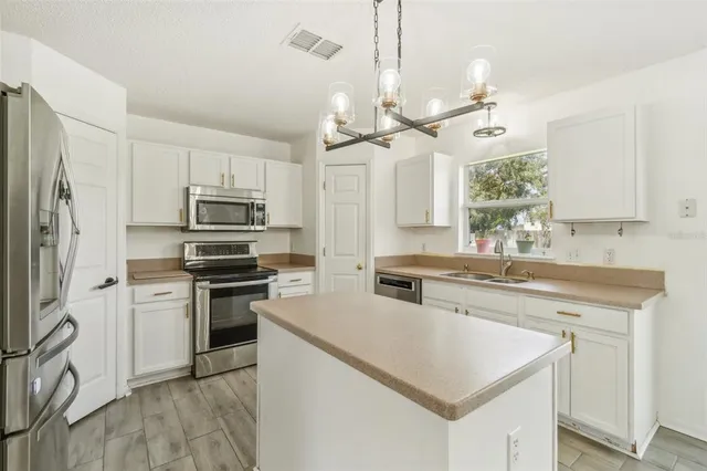 a kitchen with stainless steel appliances a stove a sink a refrigerator a center island and cabinets