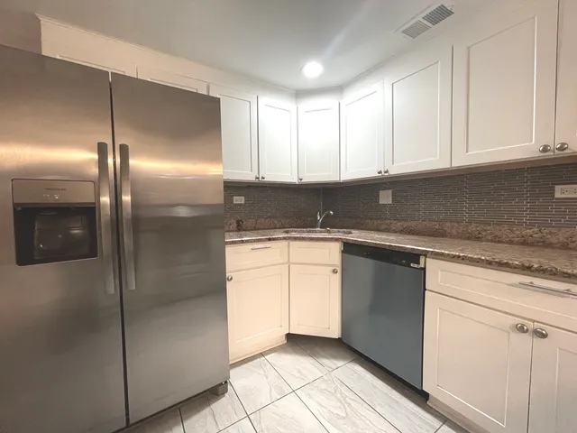 a kitchen with a refrigerator and white cabinets