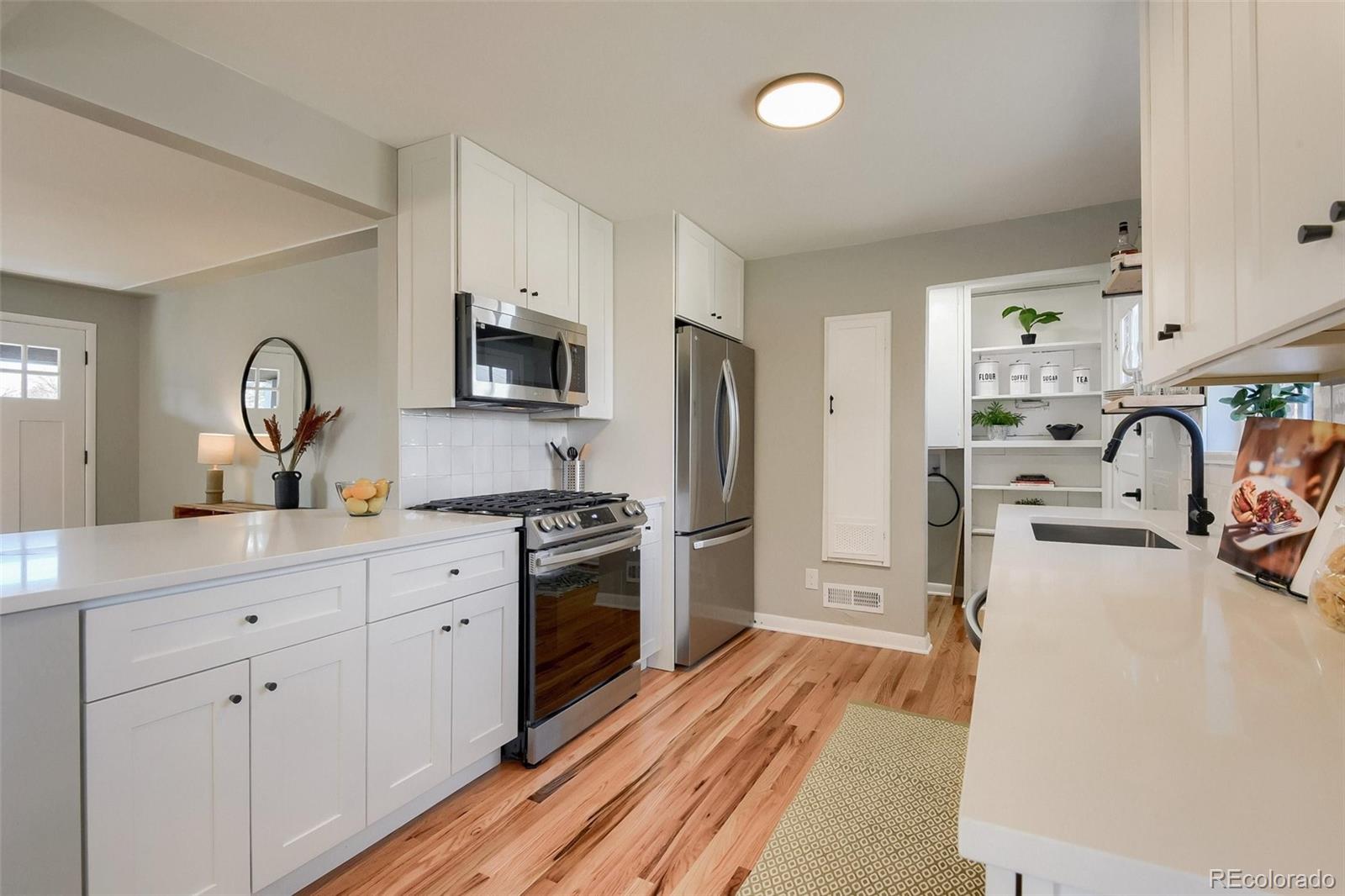 3014 Magnolia Street Denver, CO 80207 - Photo 5 of 16 a kitchen with stainless steel appliances a stove refrigerator sink and microwave