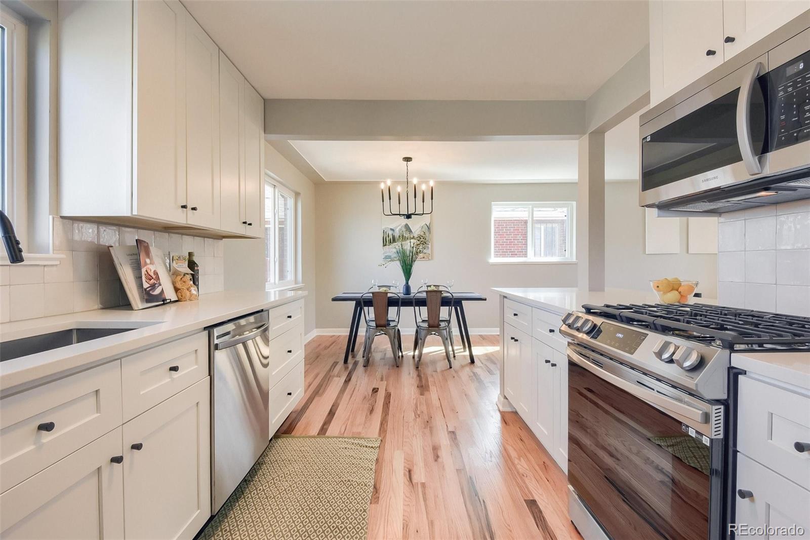 3014 Magnolia Street Denver, CO 80207 - Photo 6 of 16 a kitchen with granite countertop a stove a sink dishwasher and white cabinets with wooden floor