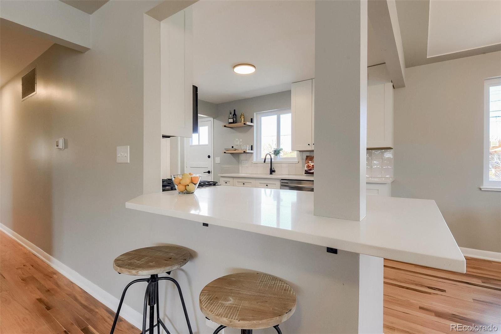 3014 Magnolia Street Denver, CO 80207 - Photo 8 of 16 a kitchen with kitchen island a sink cabinets and wooden floor