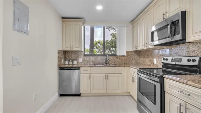 a kitchen with granite countertop white cabinets white stainless steel appliances a sink and a window