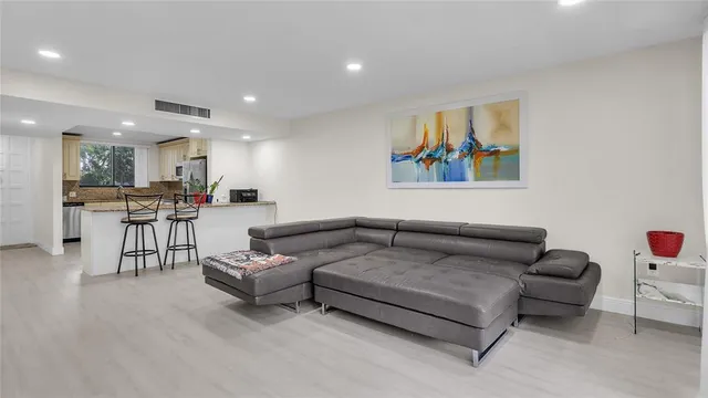 a living room with furniture and kitchen view with wooden floor