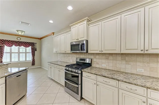 a kitchen with granite countertop white cabinets stainless steel appliances and a sink