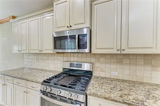 a kitchen with granite countertop white cabinets and stainless steel appliances