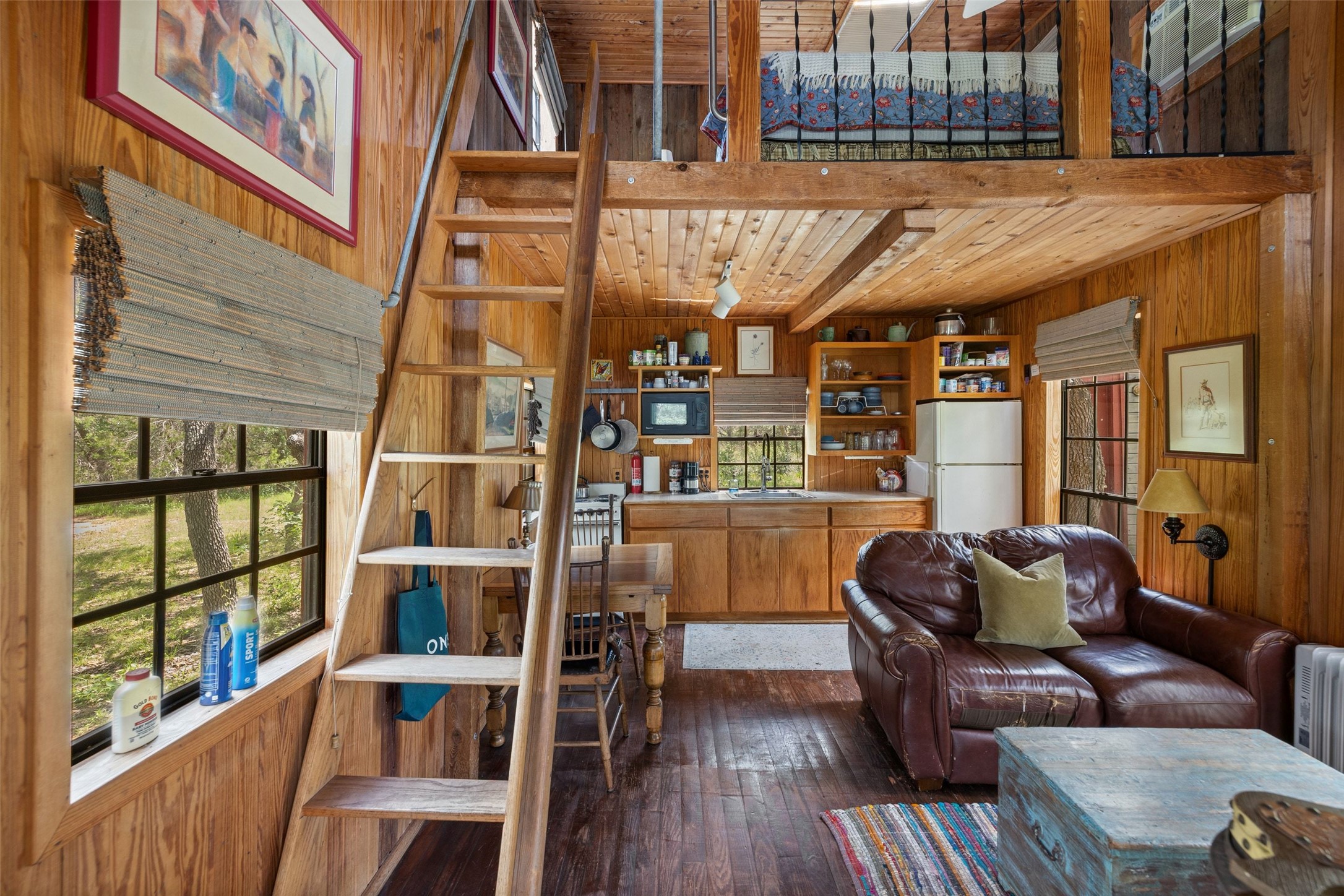 505 Red Corral Ranch Road Wimberley, TX 78676 - Photo 40 of 40 A cozy, wood-paneled interior features a functional kitchen and a sleeping loft, creating a warm, inviting atmosphere.