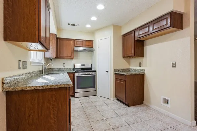 a kitchen with stainless steel appliances granite countertop a stove sink and cabinets