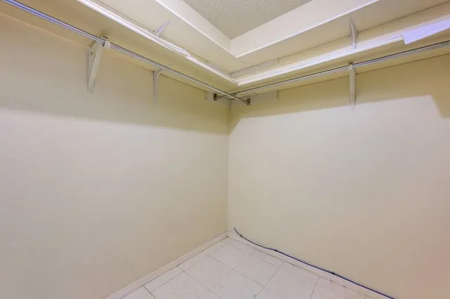 a view of an empty room with wooden floor and a chandelier fan