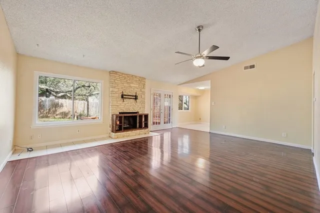 a view of an empty room with wooden floor fireplace and a window