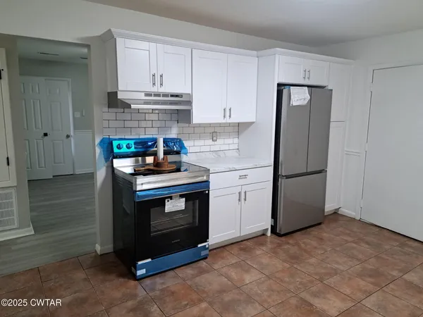 a kitchen with stainless steel appliances granite countertop a stove a refrigerator and a cabinets