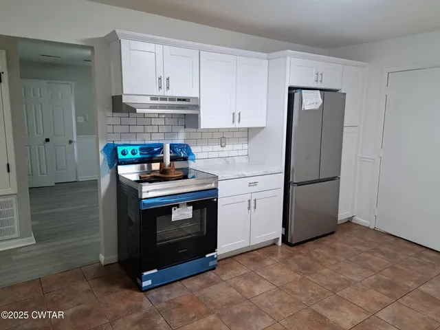 a kitchen with stainless steel appliances granite countertop a stove a refrigerator and a cabinets