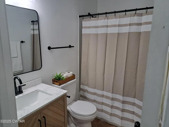 a bathroom with a sink a toilet and shower curtain
