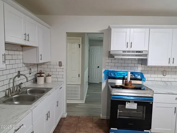 a kitchen with sink a stove and cabinets
