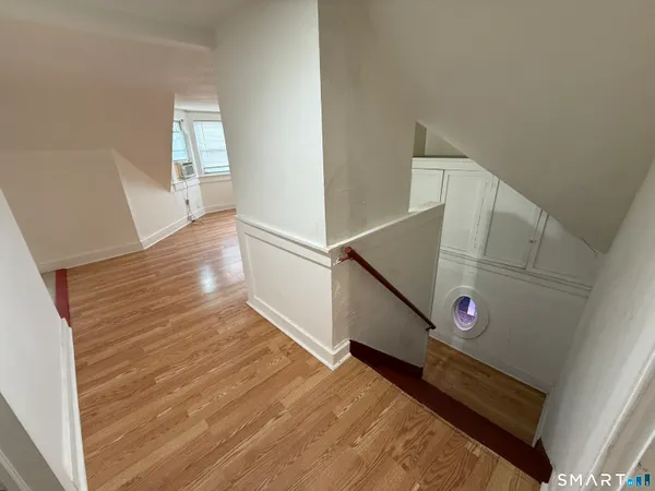a view of a hallway with wooden floor and staircase