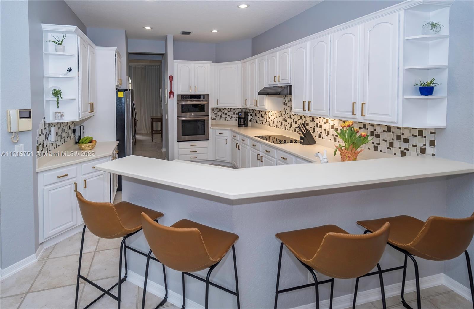 21432 Gosier Way Boca Raton, FL 33428 - Photo 14 of 55 a kitchen with stainless steel appliances kitchen island granite countertop a table and chairs in it