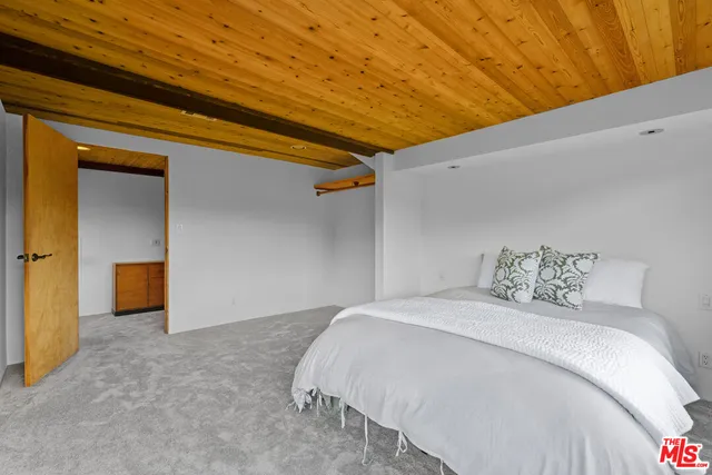 a view of a wooden house with a small yard plants and large tree
