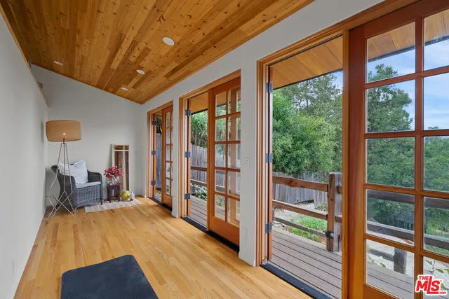 a view of a wooden house with a yard potted plants and large tree