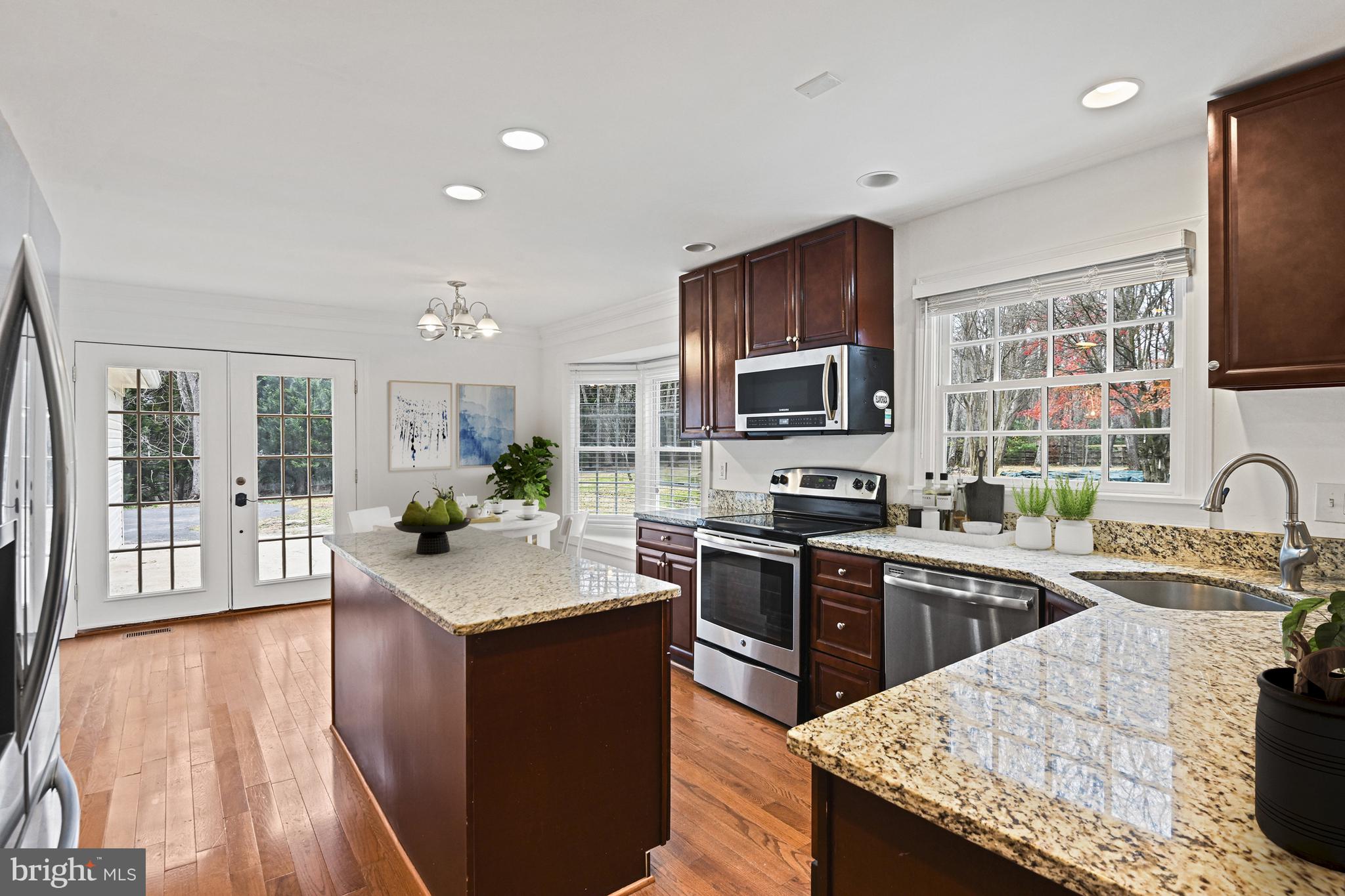 355 Springvale Road Great Falls, VA 22066 - Photo 11 of 44 a open kitchen with granite countertop a sink dishwasher stove top oven and cabinets with wooden floor