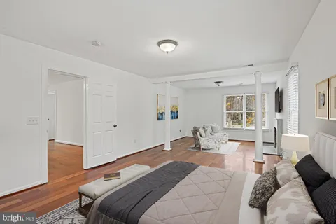 a bedroom with a bed couch and wooden floor