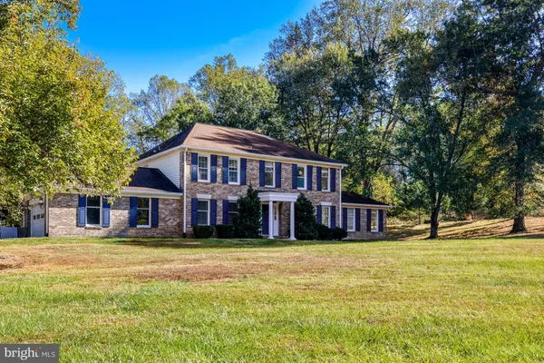 a view of a house with a big yard and large trees