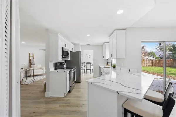 a living room with furniture a large window and kitchen view