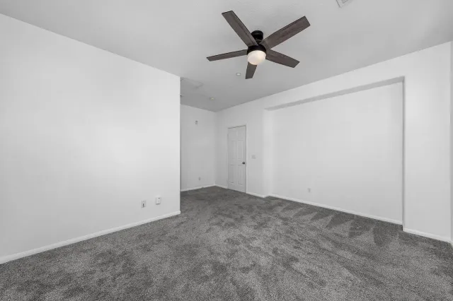 an empty room with ceiling fan and window