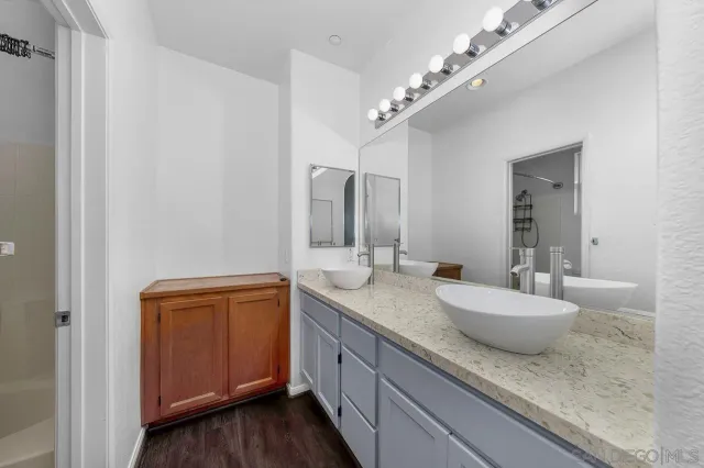 a bathroom with a granite countertop double vanity and a mirror