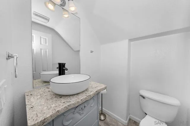 a bathroom with a granite countertop toilet a sink and a mirror