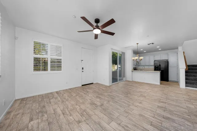 a view of empty room with wooden floor and a ceiling fan