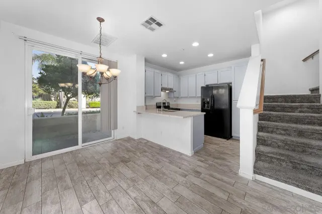 a kitchen with kitchen island a counter top space wooden floor and a refrigerator